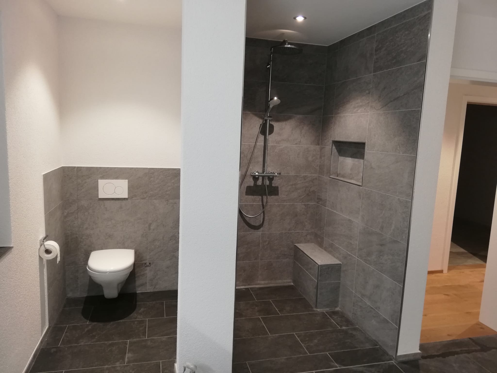 Bild von Bad in Neubau EFH, Fliesen 30x60 cm, WC und Duschnische mit Sitzbank